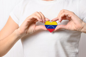 Love Venezuela. The girl holds a heart in the form of the flag of Venezuela on her chest....