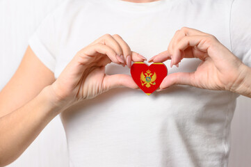 Love Montenegro. The girl holds a heart in the form of the flag of Montenegro on her chest. Montenegrin patriotism concept