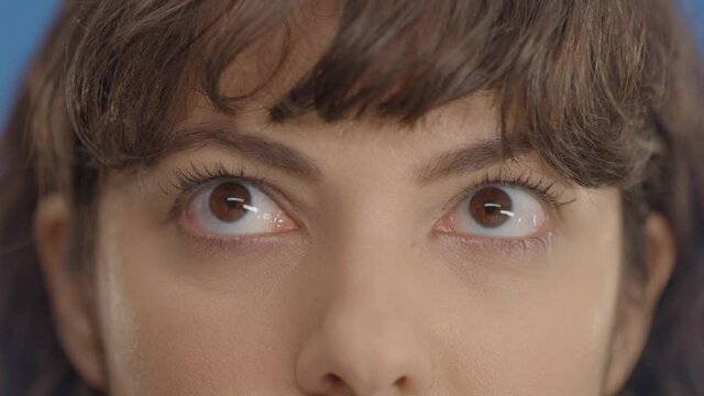 Close-up beautiful woman's eyes on a blue background.Young woman looks left and right with her eyes, makes gestures.