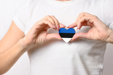 Love Estonia. The girl holds a heart in the form of the flag of Estonia on her chest. Estonian concept of patriotism
