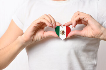 Love Mexico. The girl holds a heart in the form of the flag of Mexico on her chest. Mexican patriotism concept