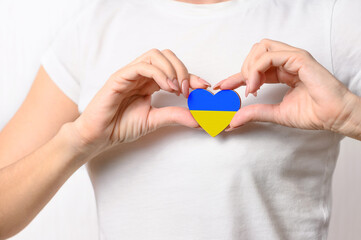 Love Ukraine. The girl holds a heart in the form of the flag of Ukraine on her chest. The concept...