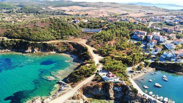 Aerial drone view of the Nea Roda situated on the Aegean sea coast, Greece. Multiple buildings with greenery, church near the shore