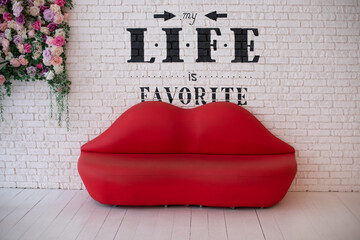 Red sofa lips shape on white brick wall background. Minimalism concept. Sofa lips in white room and...
