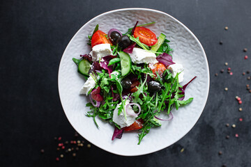 Greek salad mix vegetable tomato, cucumber, olives lettuce greens vitamin portion on the table healthy snack top view copy space food background rustic image