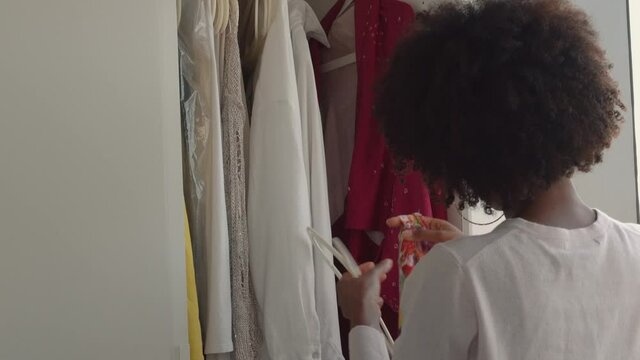 Beautiful black woman with afro choosing clothing from her wardrobe