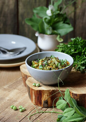 Vegan protein meal, dish of  stewed green legume vegetables: peas, green bean, broccoli garnished with parsley and flower petals, closep, overhead top down view, healthy vegan food concept
