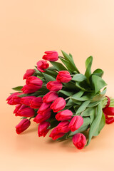 A large bouquet of red tulips lies on delicate background - spring flowers for the holiday of March 8 or Valentines Day. A postcard