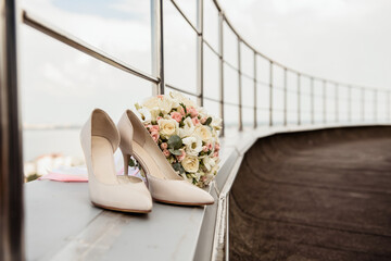 wedding stiletto shoes and bridal bouquet on the street, on the roof of the house