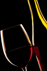 Backlit detail of a glass of red wine and the wine bottle