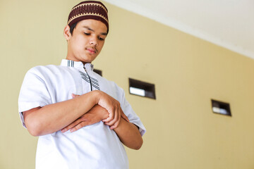 Young asian muslim man stands with hand in chest are doing salat 