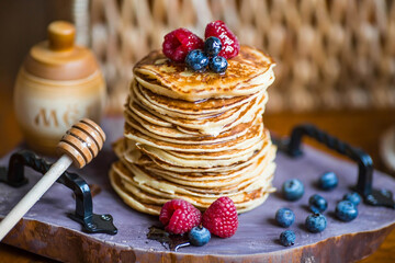 Delicious pancakes with honey, blueberries and raspberries. Russian traditions. The concept of the...