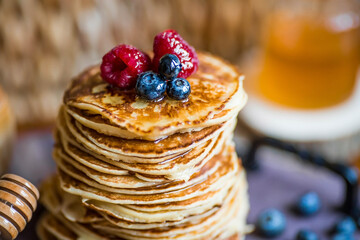 Delicious pancakes with honey, blueberries and raspberries. Russian traditions. The concept of the...