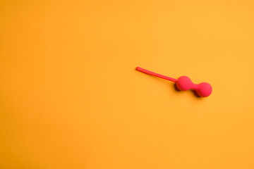 Red vaginal balls on an orange background. Adult sex toy for masturbation. Sex shop concept