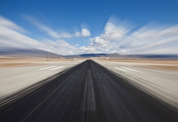 Desert airport runway with dark skid marks and motion blur.