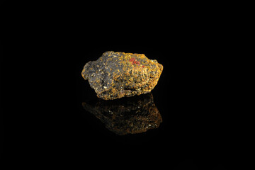 Natural mineral rock specimen - raw stone orpiment on black glass background from Haidarkan, Kyrgyzstan.