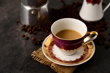 Cup of coffee with milk in gold porcelain cup, coffee beans.