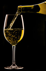 Pouring a glass of wine on black background.