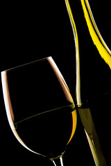 Backlit detail of a glass wine and the wine bottle
