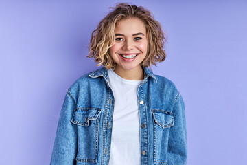 female with wavy short hair smiling and looking at camera, wearing casual denim wear. isolated...