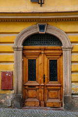 Colorful old elegant front wooden carved entrance yellow door with glass inserts, stone portal with floral ornament, picturesque street with baroque and renaissance historical buildings