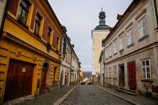 Narrow medieval picturesque street with baroque and renaissance historical buildings in winter day, bell tower of church of St. Nicholas, Bohemian Paradise, Turnov, Czech Republic