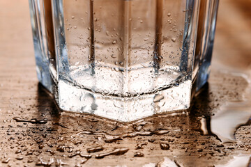 empty glass on a table in a puddle of water with many drops