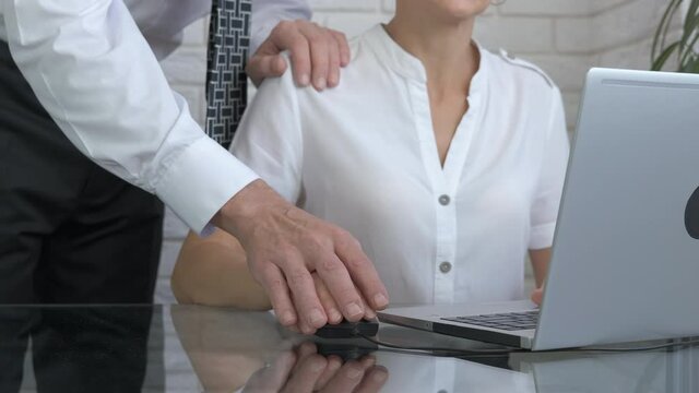 Boss touch his office worker. A boss touch the woman shoulder and try to help her with computer.