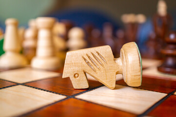 Fallen chess knight piece on a chessboard © Mirco Vacca/Wirestock