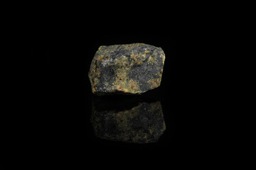 Natural mineral stone - piece of Serpentine, Lizardite gemstone from Bajenovo, Ural, Russia on black glass background.