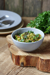 Vegan protein meal, dish of  stewed green legume vegetables: peas, green bean, broccoli garnished with parsley and flower petals, closep, overhead top down view, healthy vegan food concept