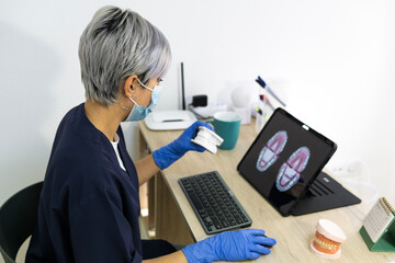 Dental technician designing new dental prosthesis on the computer in his laboratory