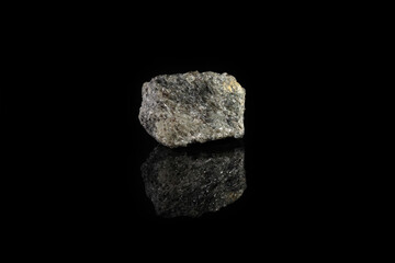 Fototapeta premium Natural mineral from geological collection - raw apatite, phosphorus ore stone from Khibiny, Kola Peninsula, Russia on black glass background.
