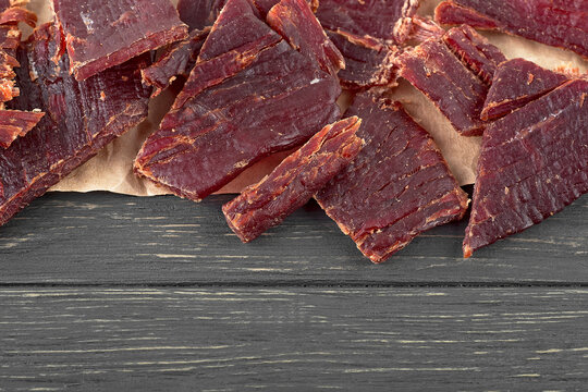 Close Up View Of Beef Jerky Pieces On A Wooden Table, Top View.