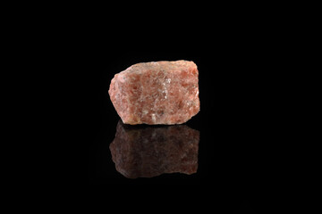 Natural mineral rock specimen - pink marble from Slyudyanka, Baikal, Russia on black glass background.