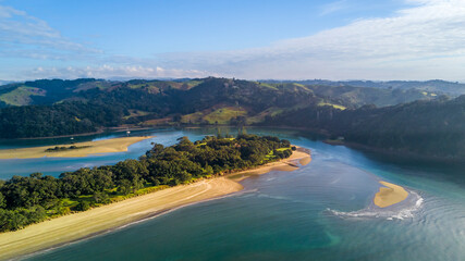 Aerial view of a beautiful river running through a green hillside to the Tasman sea. Auckland New Zealand.