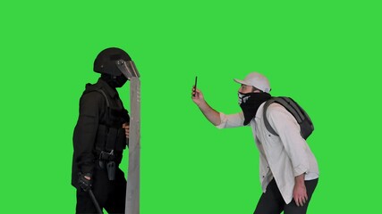 Aggressive protester shooting riot police on smartphone on a Green Screen, Chroma Key.