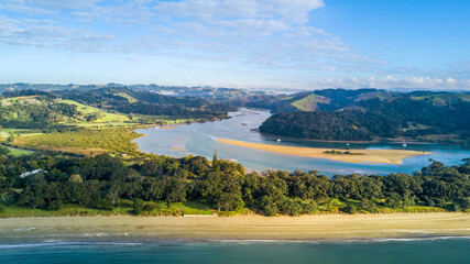 Aerial view of a beautiful river running through a green hillside to the Tasman sea. Auckland New Zealand.