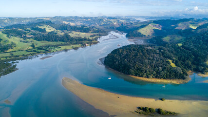 Aerial view of a beautiful river running through a green hillside to the Tasman sea. Auckland New Zealand.