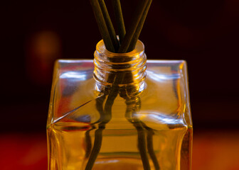 Fototapeta na wymiar Closeup of bottleneck of small glass bottle with aroma sticks in it