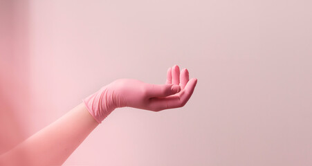 Female hand in vinyl glove above pink background