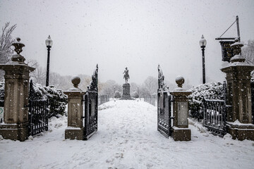 George Washington statue in the Boston Commons during a snow storm framed by park entrance gates