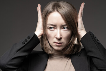 Refusal gesture to hear something. Woman covers her ears with her hands. She doesn't want to hear anything. Businesswoman refuses to listen. A woman in a business suit hears nothing.