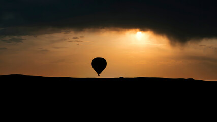 Cappadocia, Turkey - August 2017: Silhouettes of hot air balloons flying in Cappadocia landscape with dramatic morning sky, Turkey