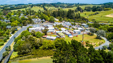 Aerial view of a little village in the middle of the countryside spotted with farms and forest. Auckland, New Zealand.