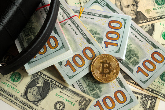 Metal bitcoin cripto money and black bag on American dollar banknotes,above view