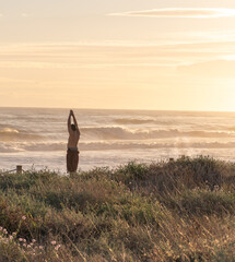 Naklejka na ściany i meble person meditating on the beach surrounded by nature