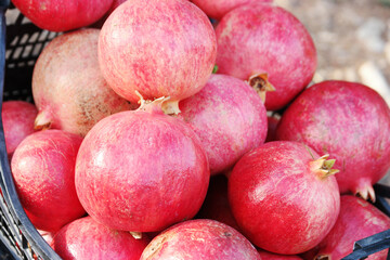 Heap of healthy pomegranate fruits in box. Pile of fresh organic fruits close up. Pomegranate...