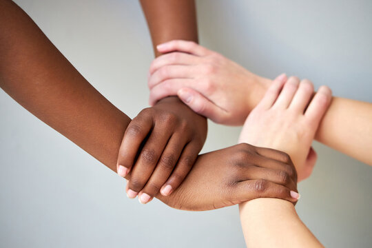 close up of diverse female hands holding together isolated over grey background. diversity, support, friendship concept.
