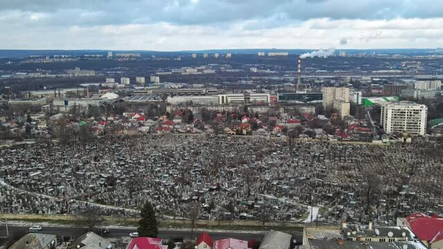 Aerial drone view of a cemetery in Chisinau, Moldova. Multiple graves, crypts, walkways. Cityscape on the background. Cloudy weather, bare trees, winter